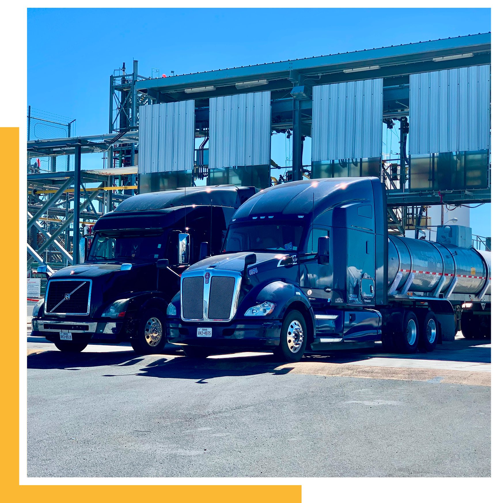 Two black trucks parked at industrial site.